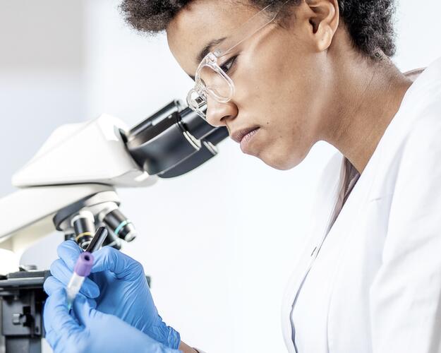 Scientist standing next to microscope