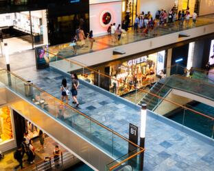 Various levels of a shopping mall with shop windows and people