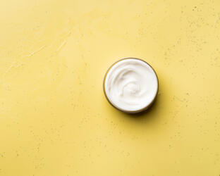 Jar of skin cream on yellow surface