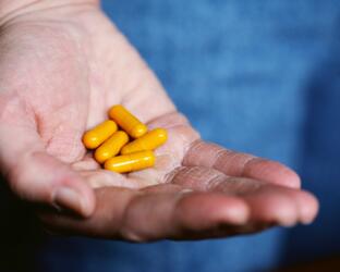 Hand holding yellow pill capsules
