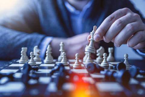 Person playing chess, about to place the white queen