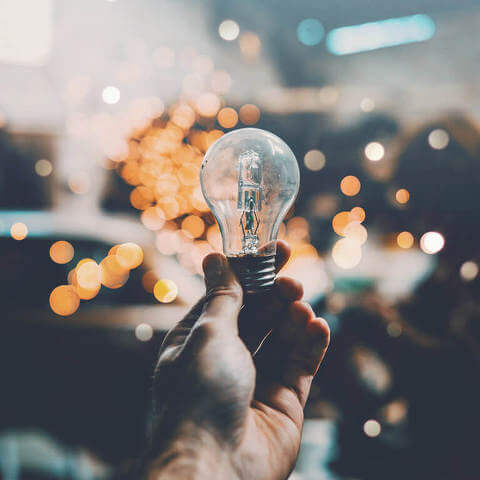 Hand holding a lightbulb with bokeh background effect