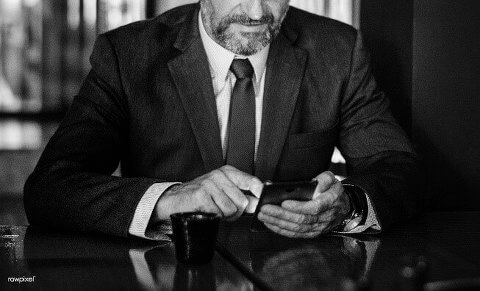 Black and white photo of a business man using phone in cafe