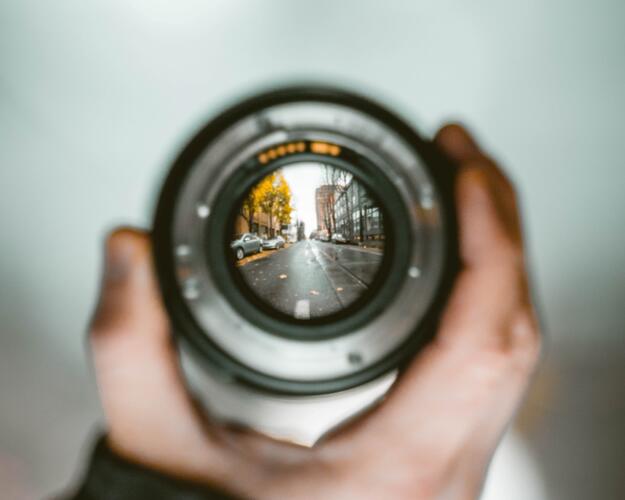 Person holding camera lens