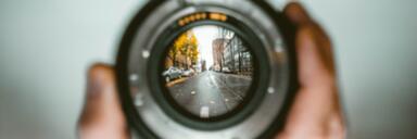 Person holding camera lens