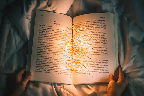 Reel of lights lying on an open book, held open by someone